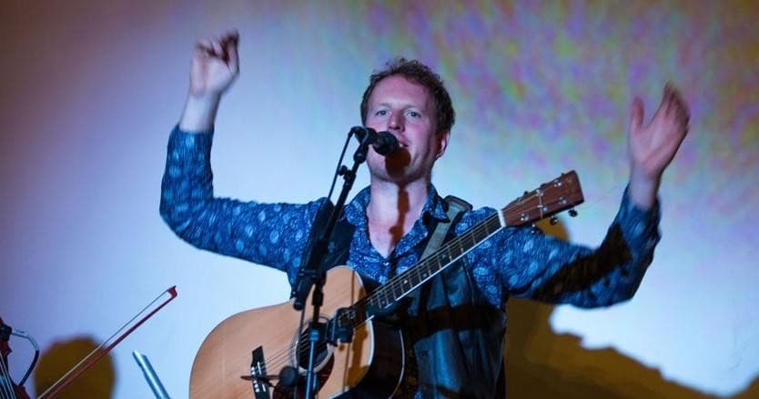 Solo musician singing with guitar on intimate pub stage