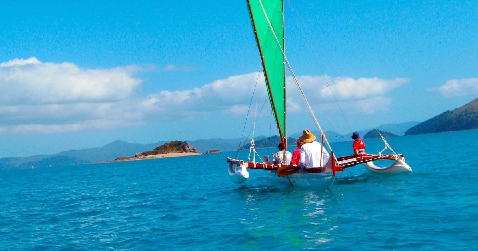 Outrigger sailing near tropical Whitsundays island on turquoise sea