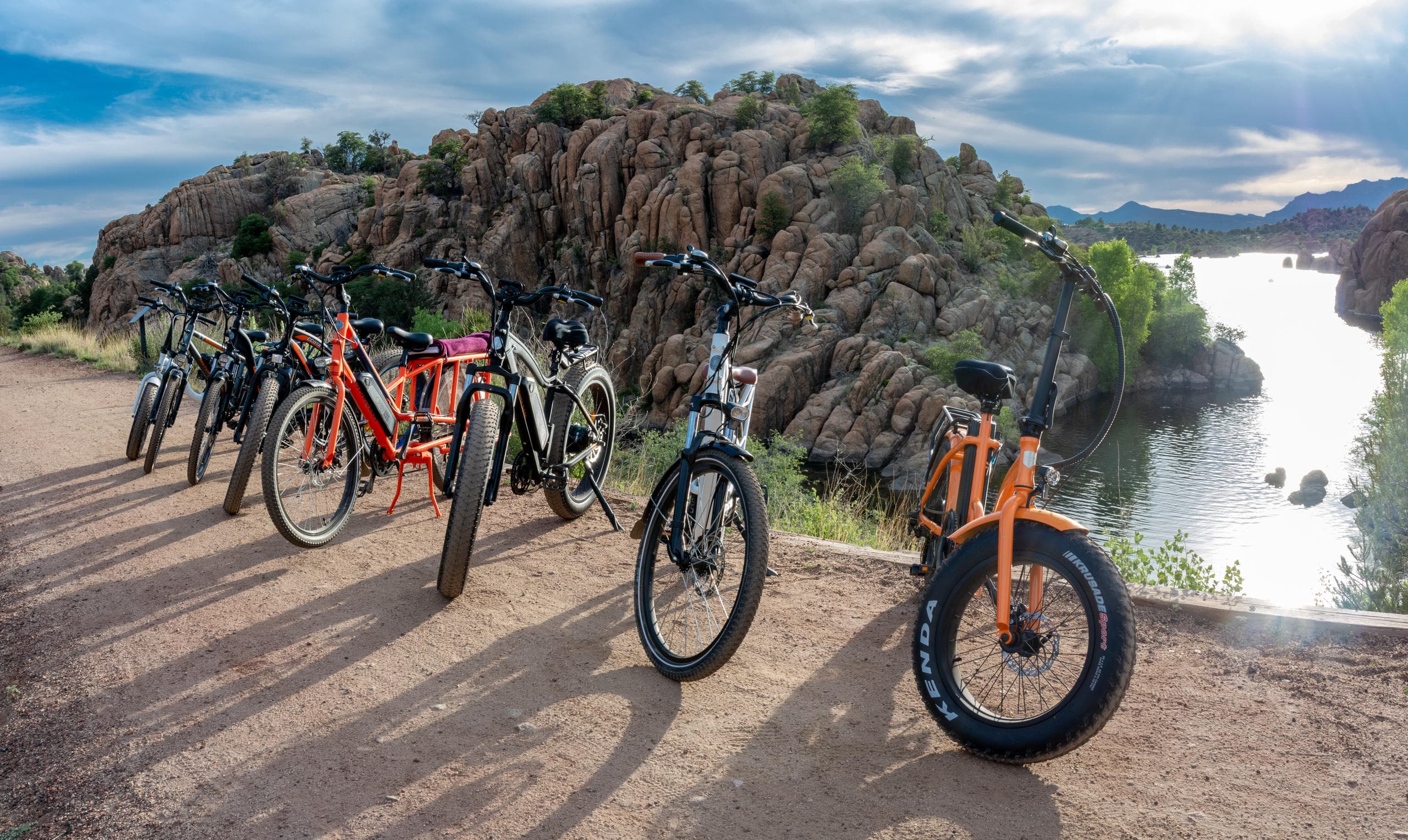 Electric bikes lined along rocky lakeshore with scenic water views