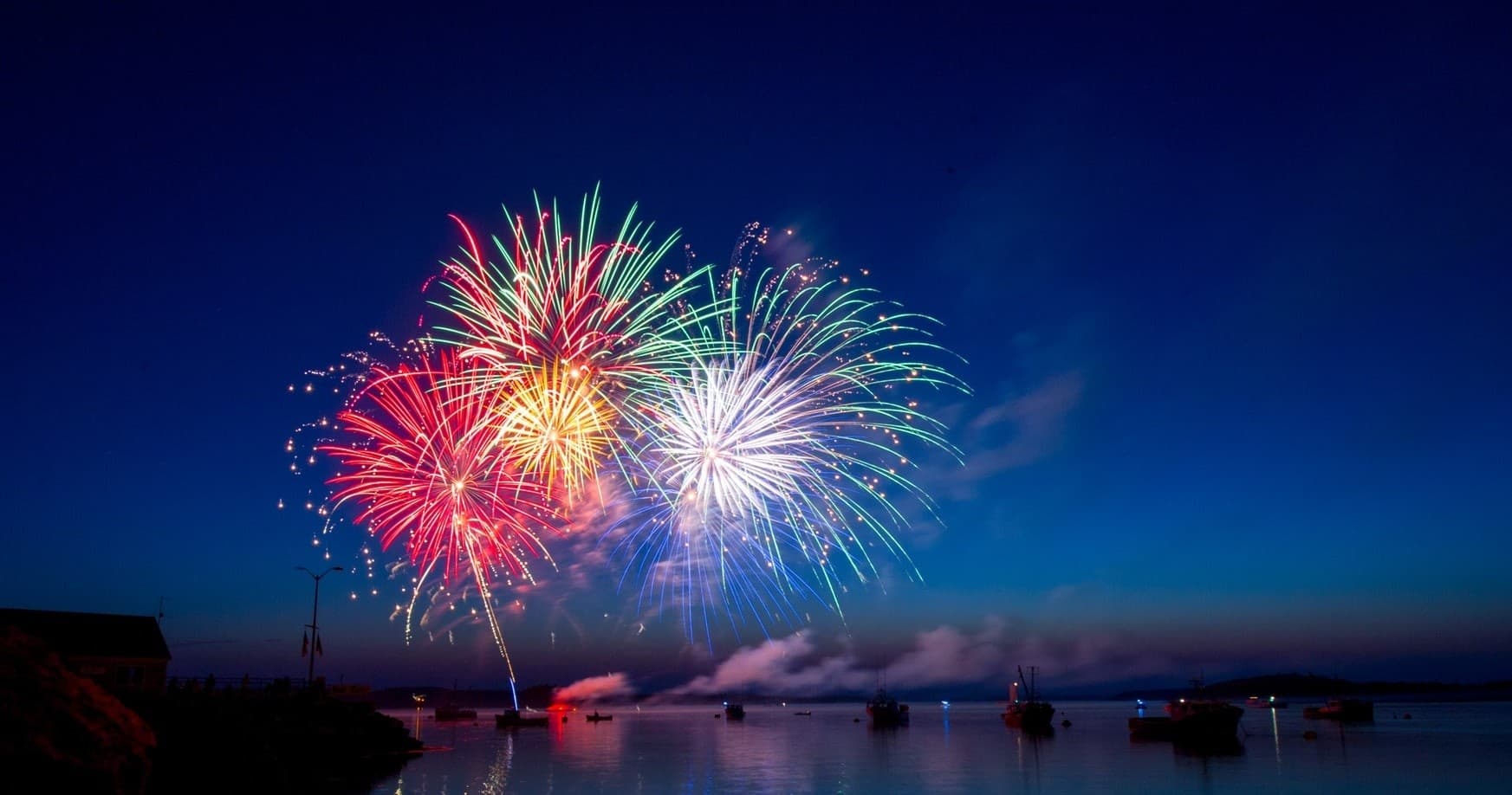 Fireworks display over harbor at night with boats
