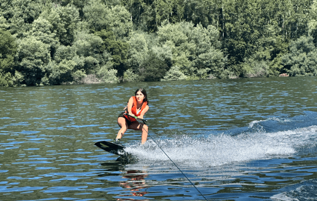 Waterskier being towed across a lake with green tree shore