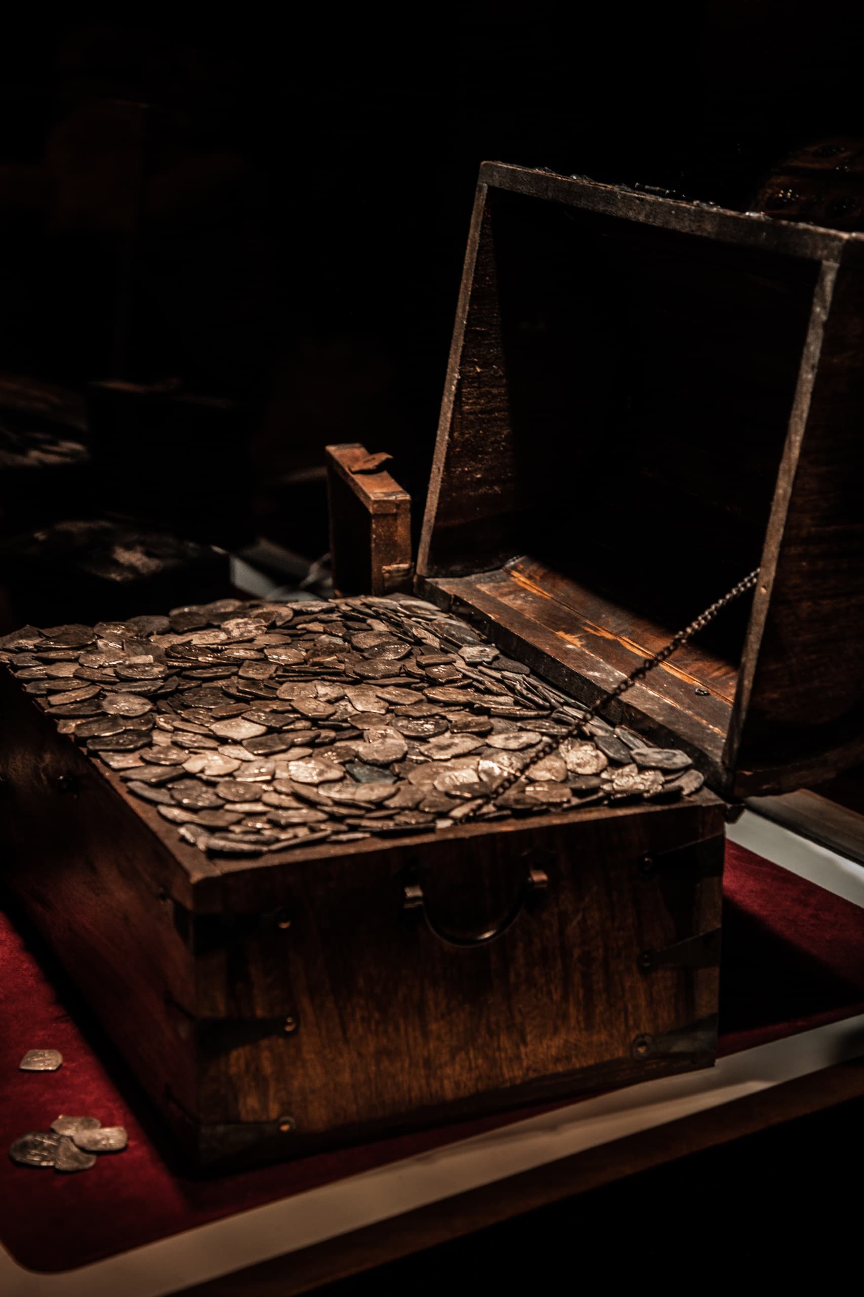 Open treasure chest filled with old silver coins in museum exhibit