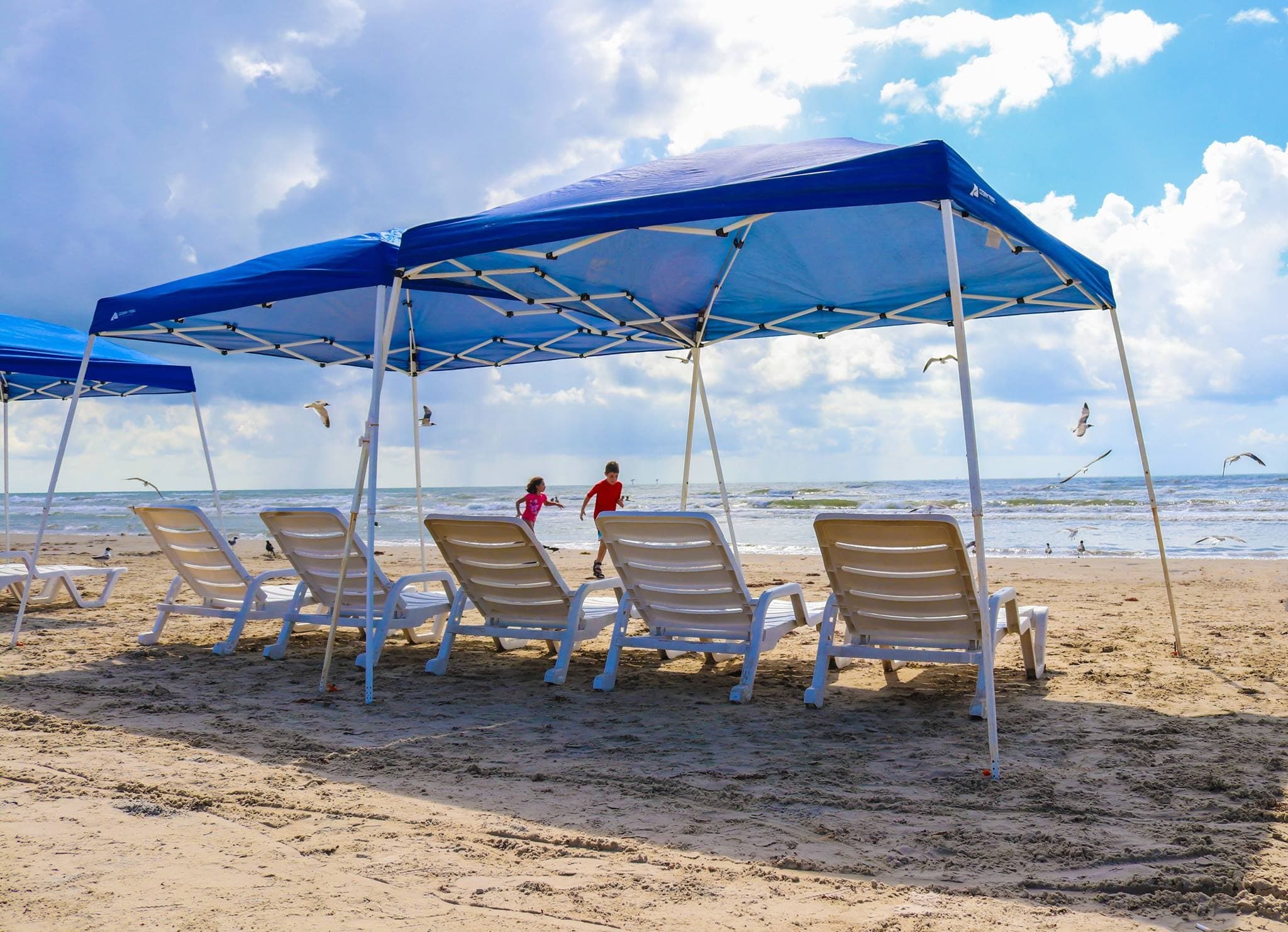 Beach lounge chairs under canopy for shaded oceanfront relaxation