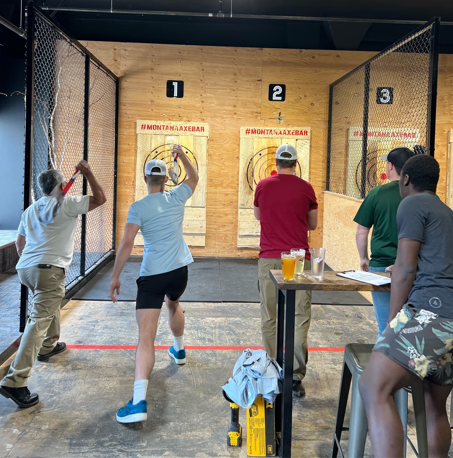 People throwing axes in indoor axe-throwing lanes at Montana Axe Bar