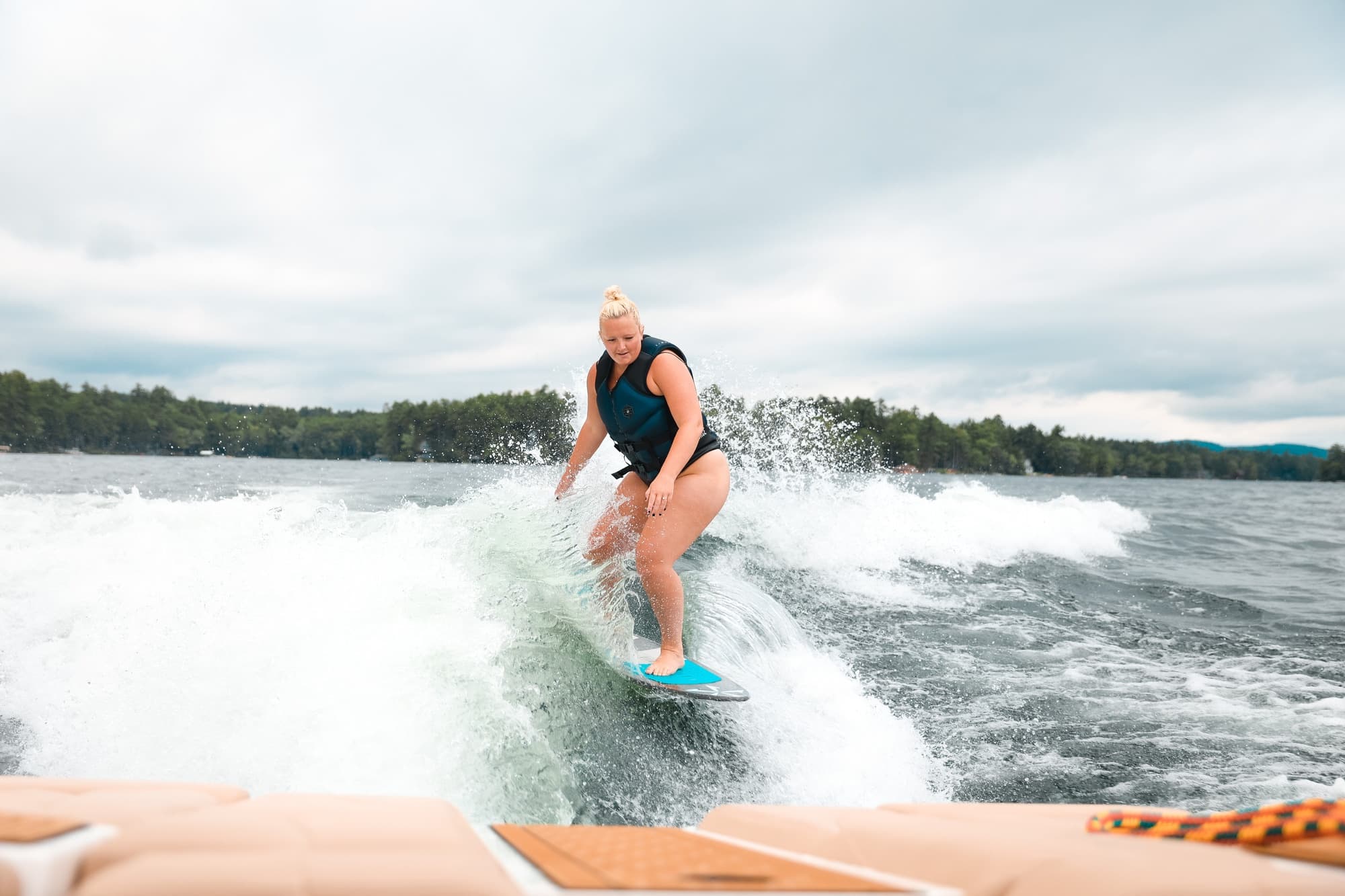 Female wakesurfer cutting wake behind boat on lake