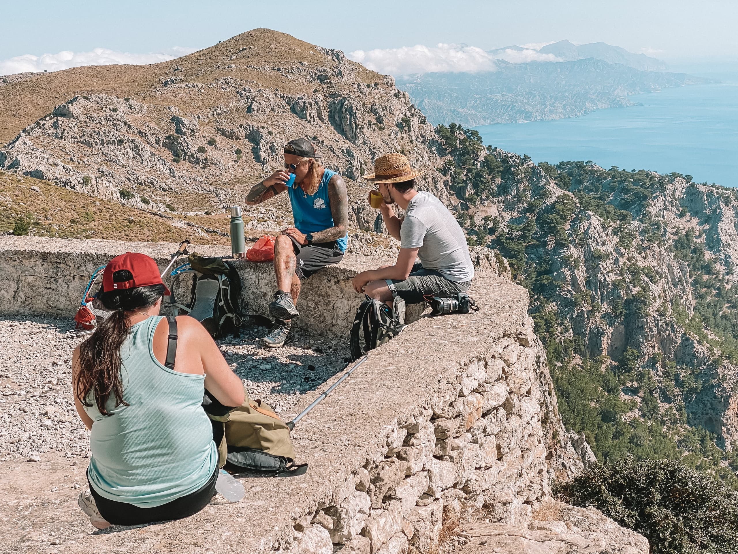 Hikers resting on coastal cliff with panoramic sea view in Greece
