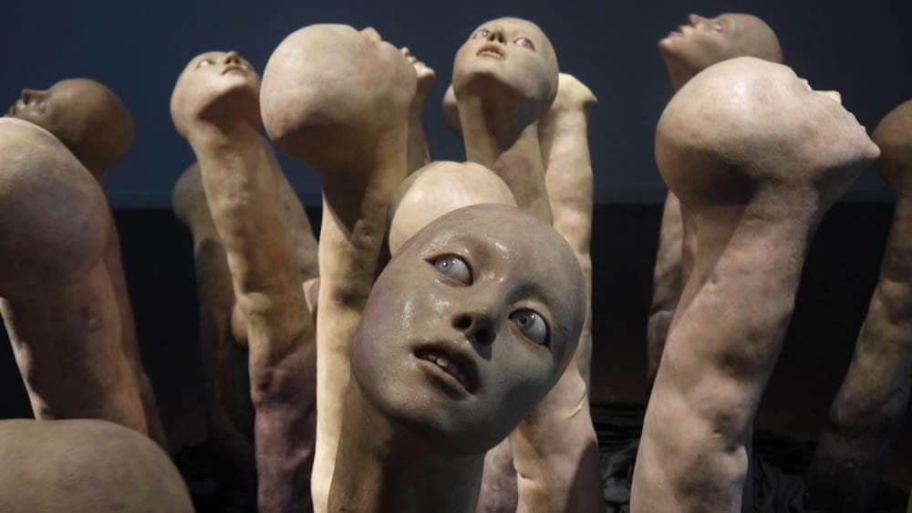 Eerie sculpted heads installation in dim room for haunted exhibit