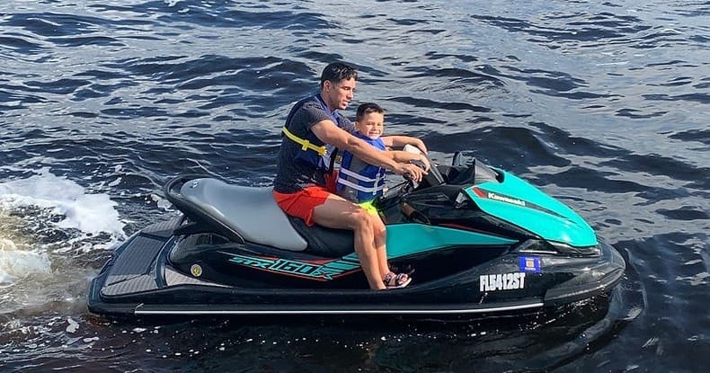 Two riders on jet ski speeding across open coastal waters
