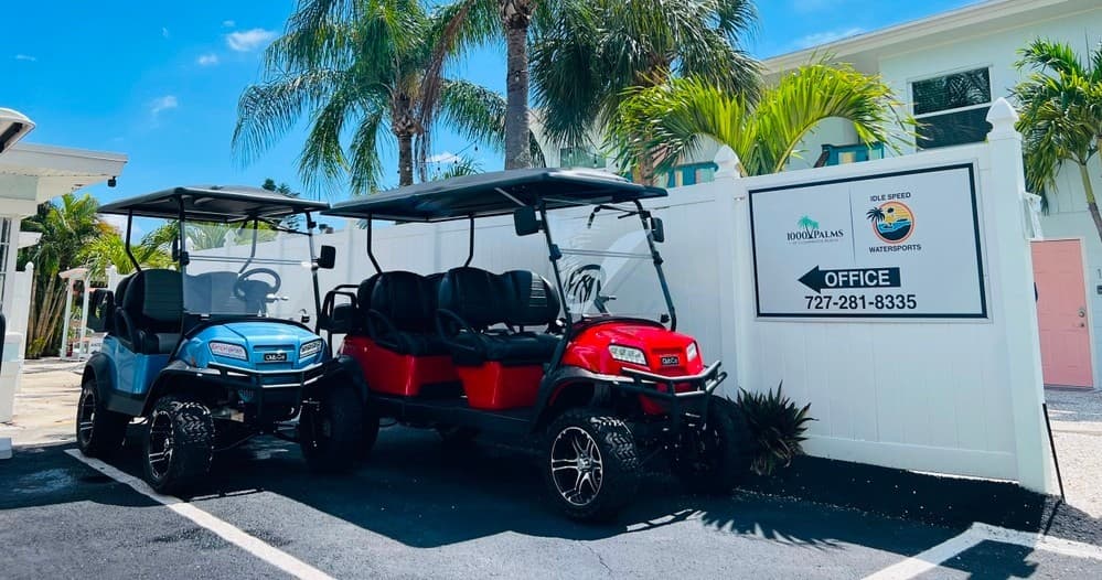 Golf carts parked outside watersports office beneath palm trees