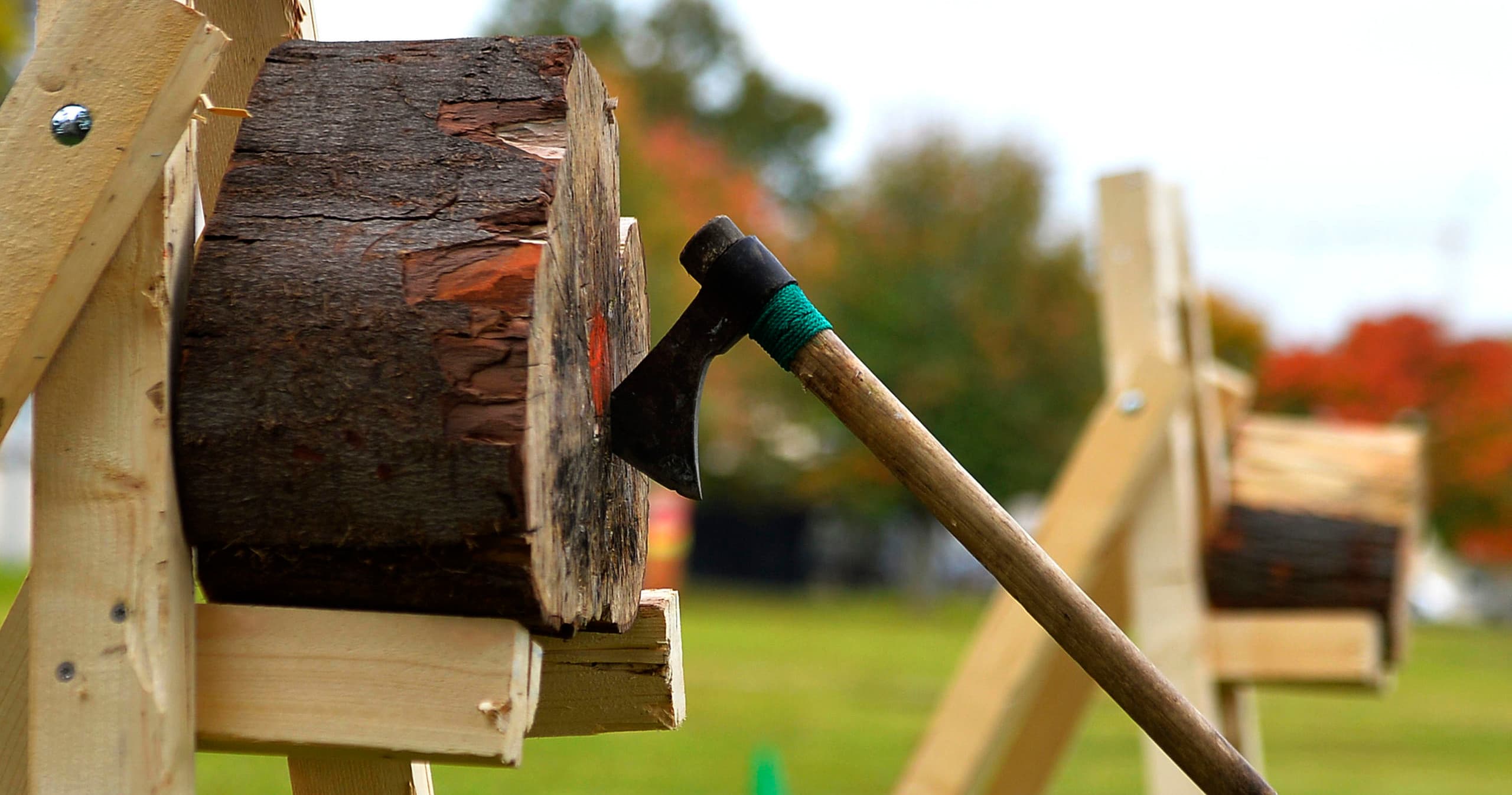 Axe embedded in outdoor target log at axe-throwing range