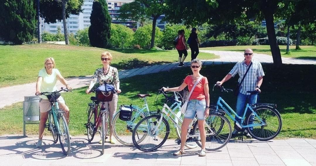 Friends on rental bikes standing in leafy city park gathering