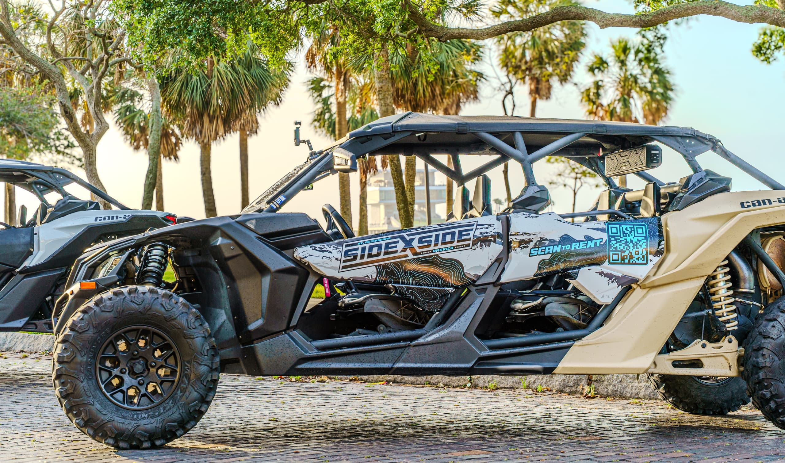Close-up side-by-side UTV on coastal cobblestone with palms