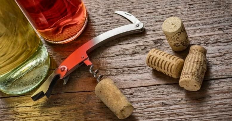 Corkscrew and wine corks on wooden table at tasting setup
