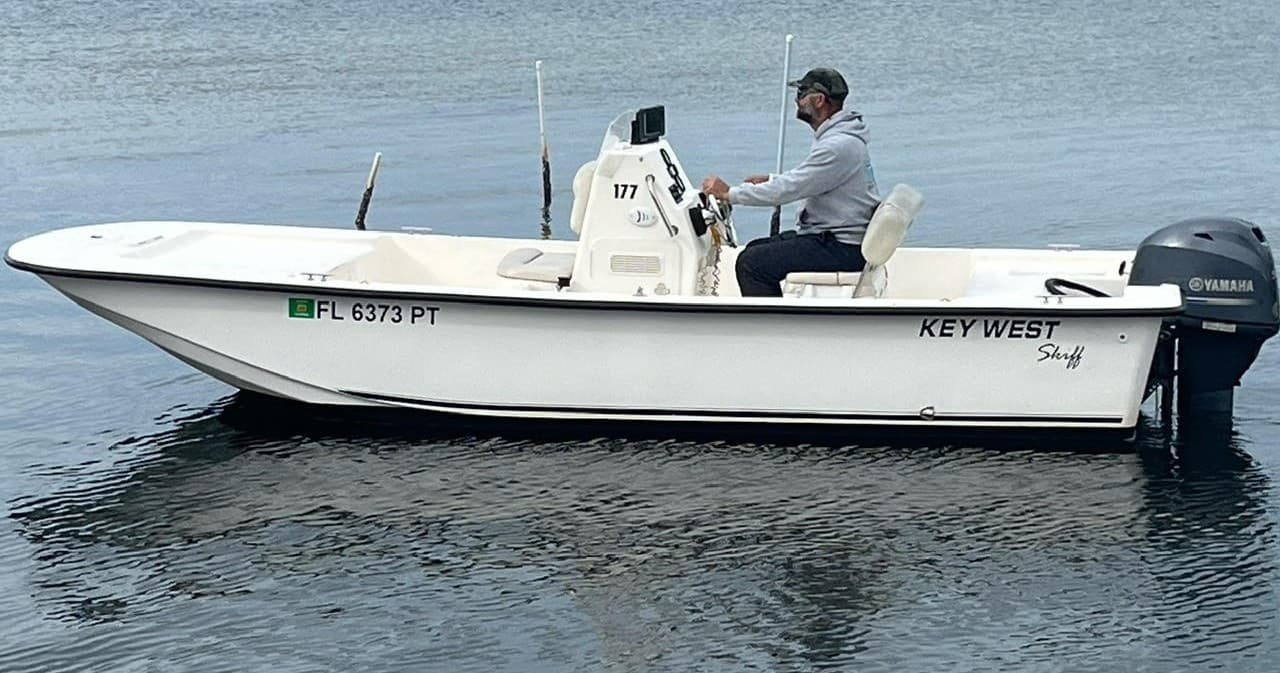 Small center-console Key West boat on open coastal water, angler driving