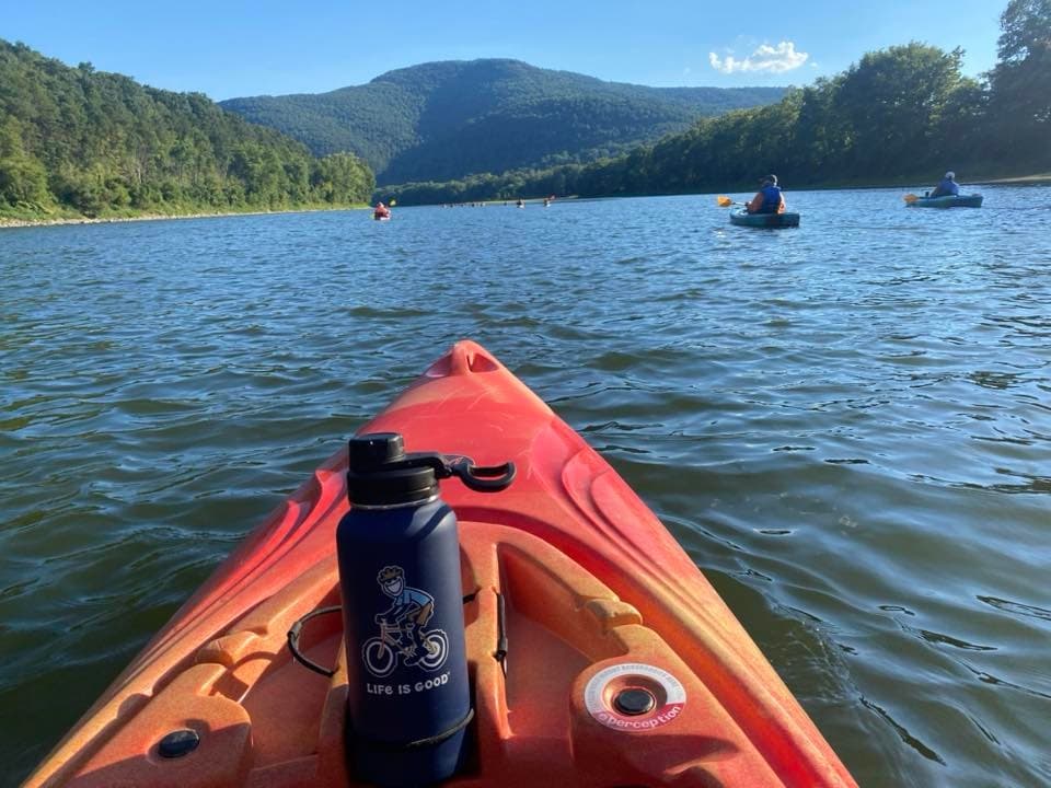 Solo kayak bow on mountain lake, paddling toward forested hills