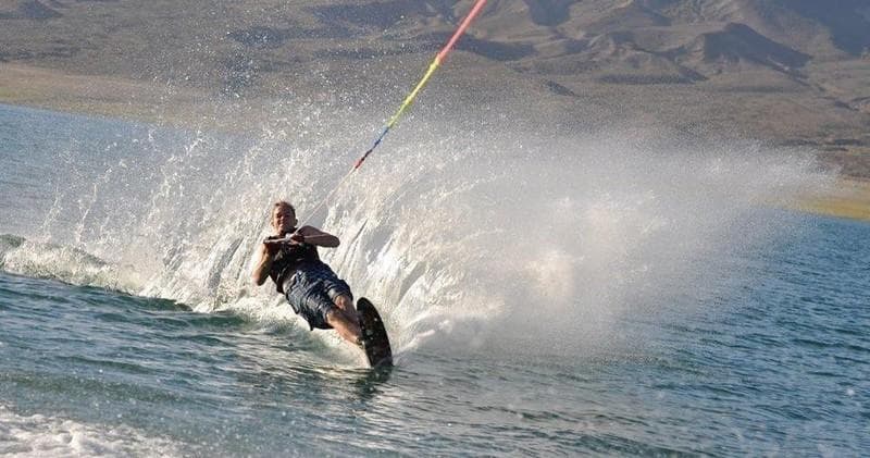 Wakeboarder spraying water while being towed on lake