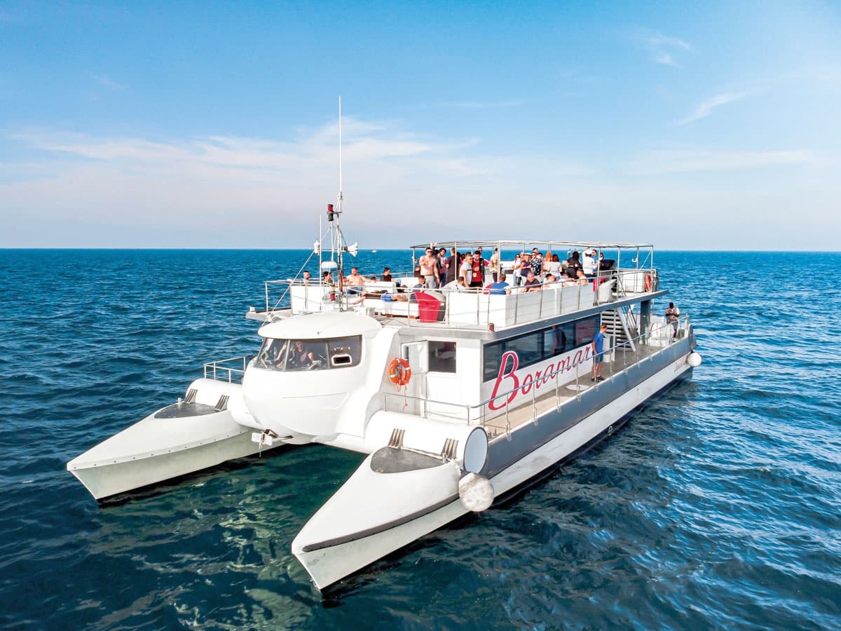 Twin-hull tour catamaran navigating open ocean with guests