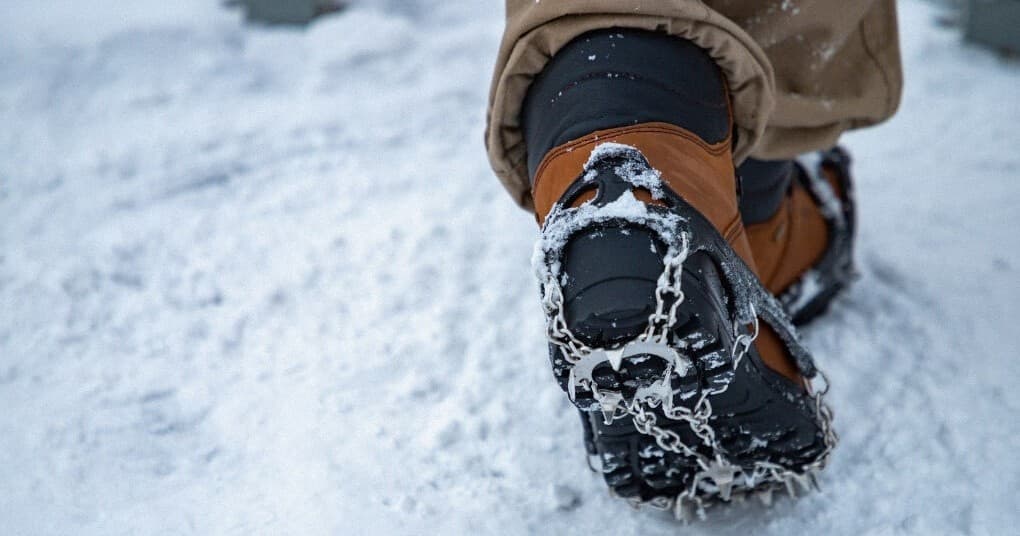 Boot with traction cleats stepping on packed winter snow