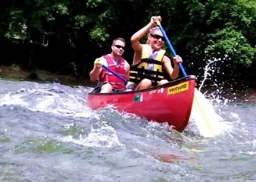 Canoeists navigating whitewater rapids wearing life jackets and paddling