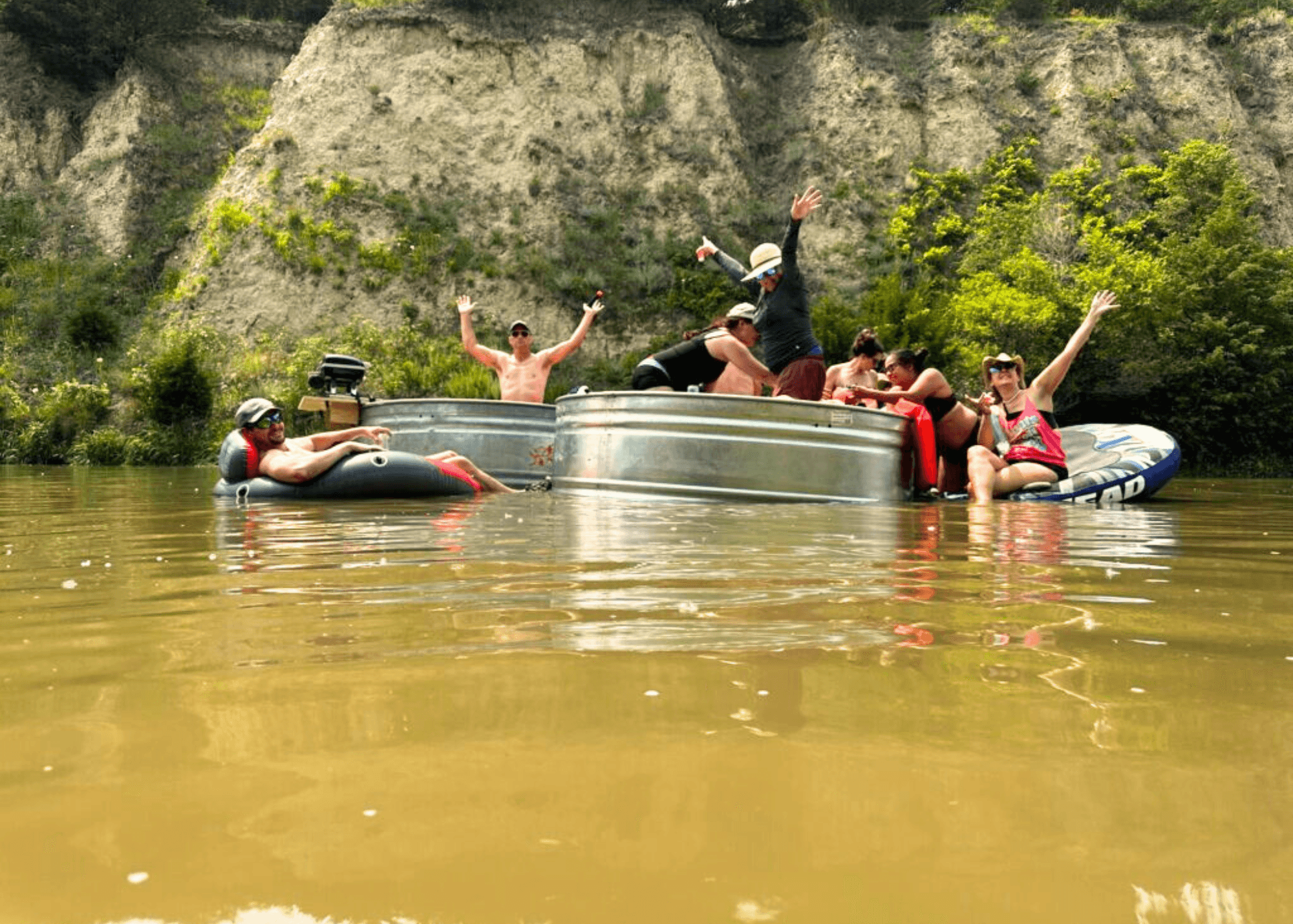 Group floating on pontoon and tubes in scenic river canyon party