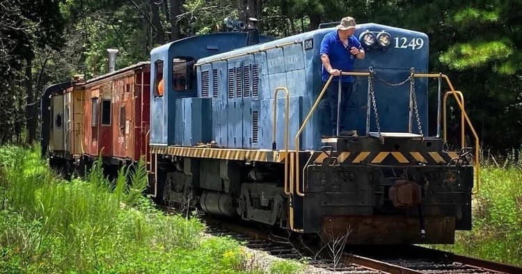 Blue diesel locomotive rolling through wooded countryside