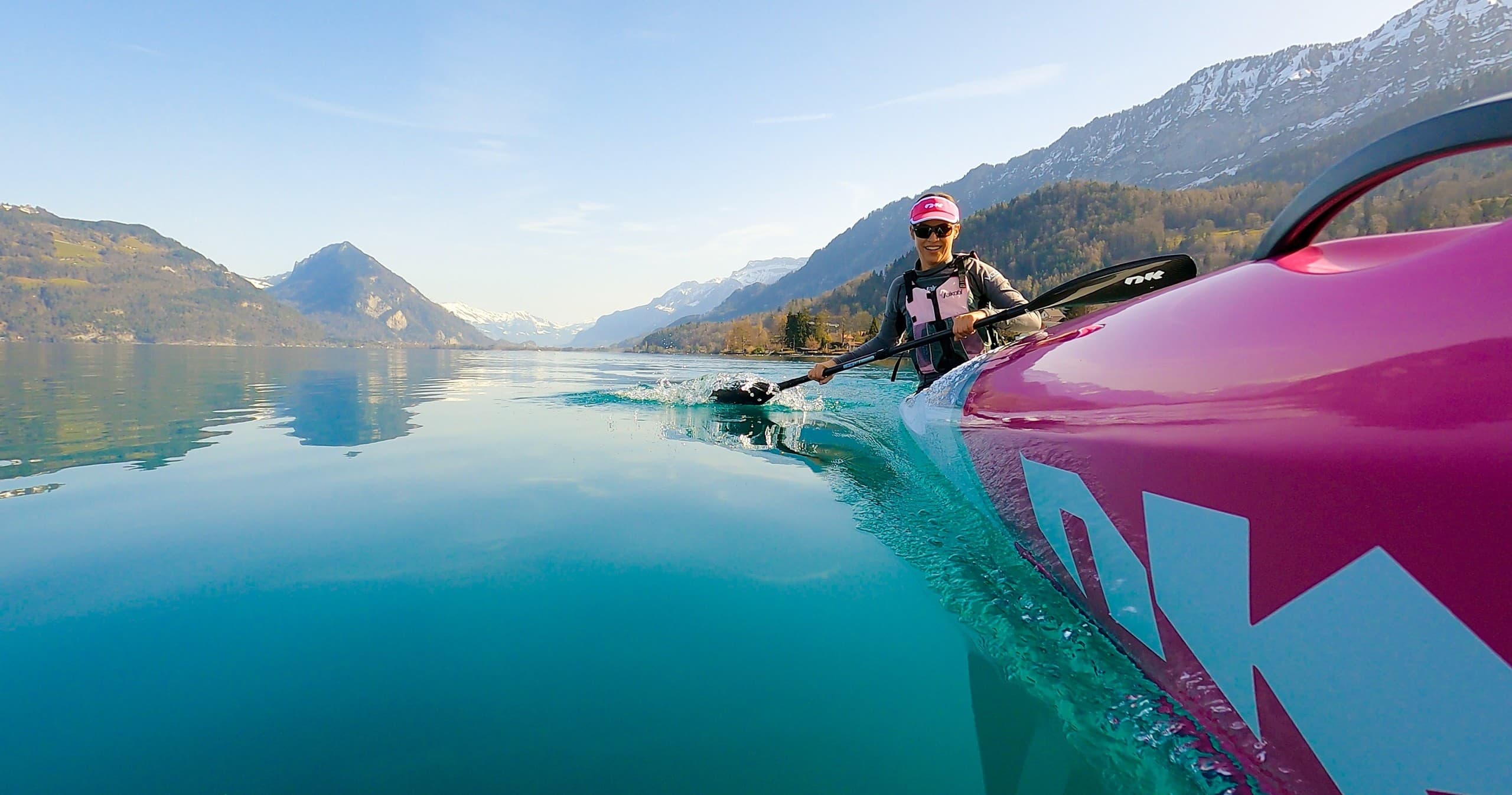 Kayaker taking serene alpine lake tour with mountain vista