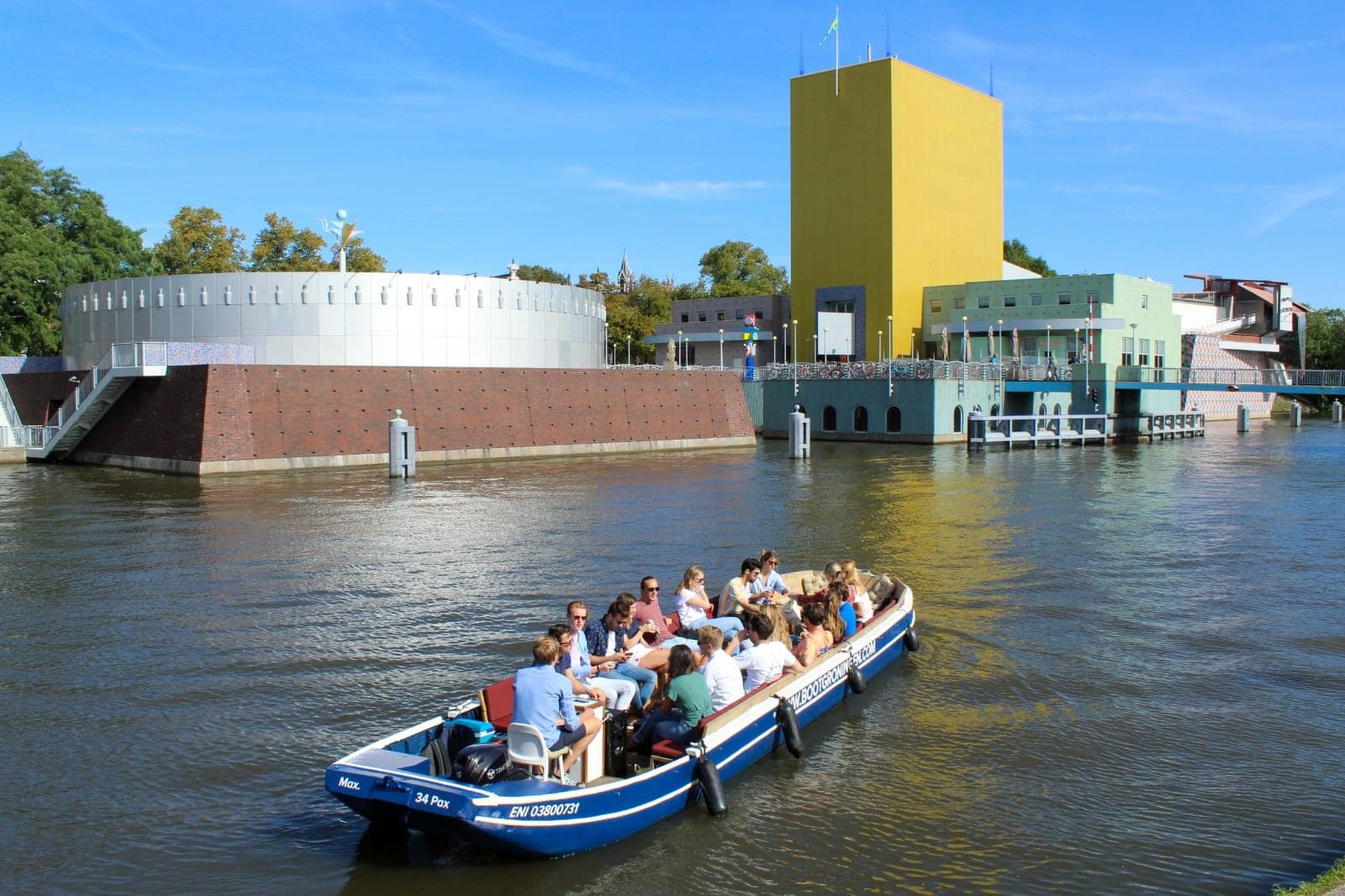 Open boat tour on Groningen river with modern waterfront building