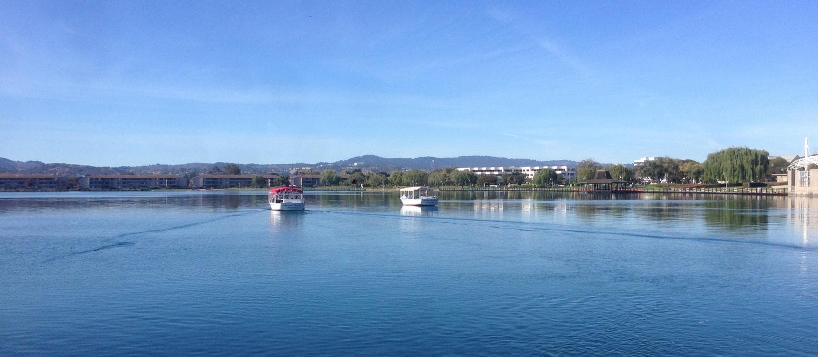 Panoramic calm lake view with distant shoreline and docked boats
