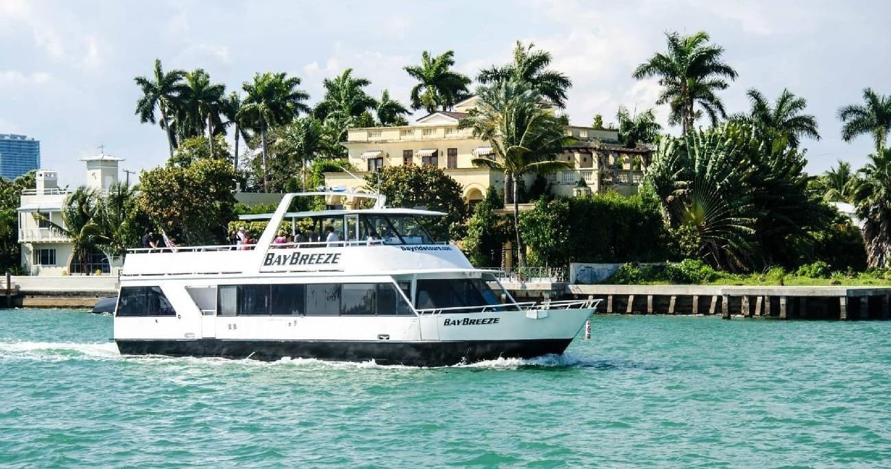Passenger boat on turquoise water by Miami palm trees and villas