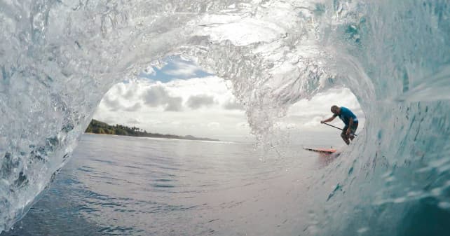 Surfer carving inside a blue barreling wave over reef break