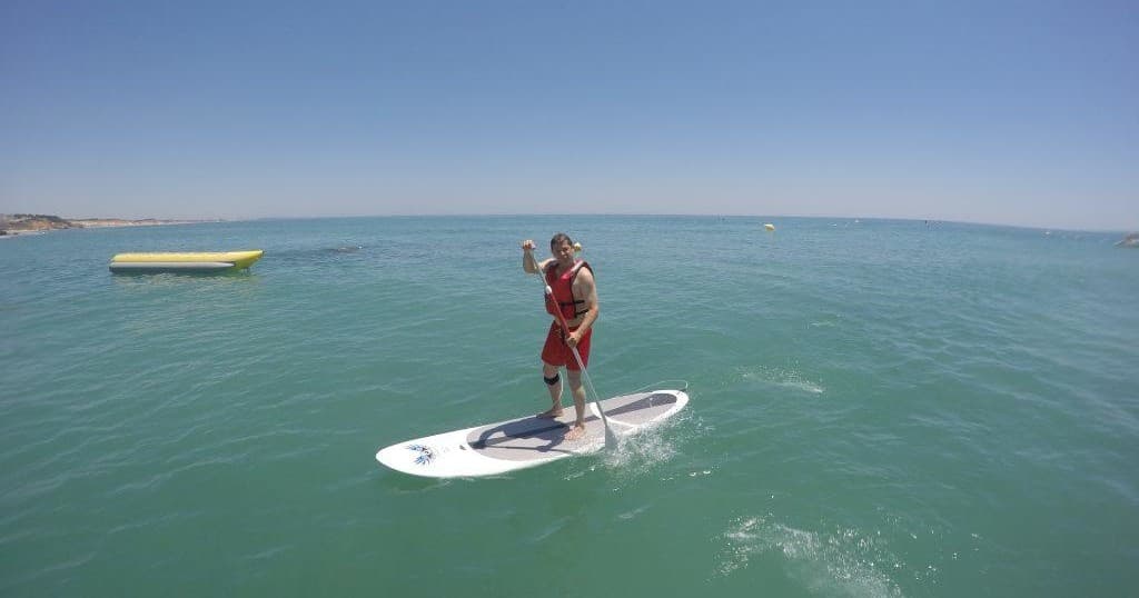 Person paddleboarding on calm turquoise sea with distant horizon