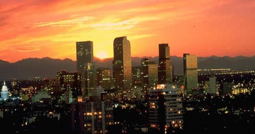 City skyline at sunset with glowing buildings and mountains