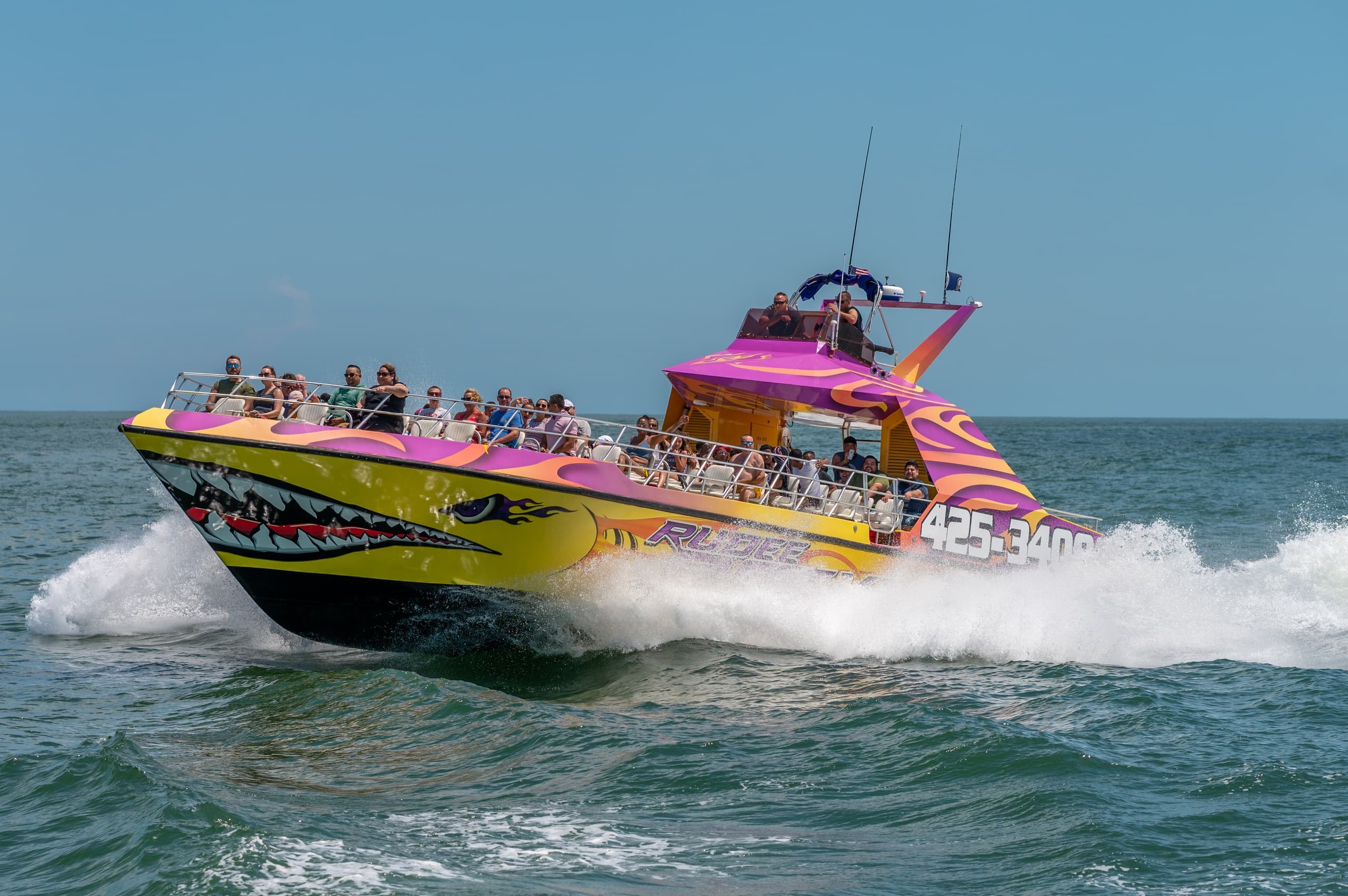 High-speed colorful tour boat cutting through coastal waters