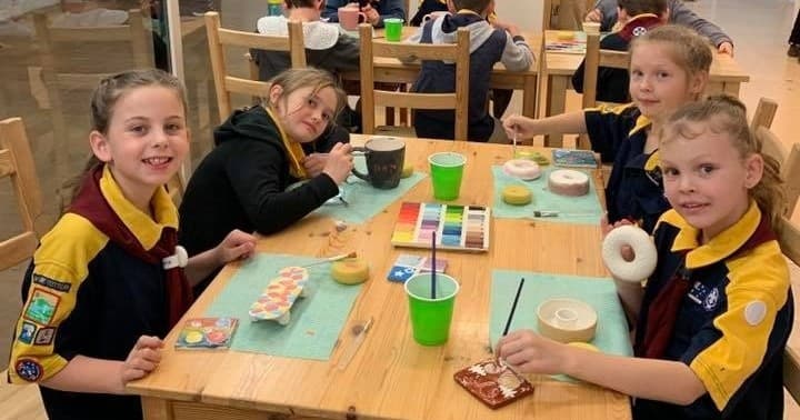 Children painting pottery at indoor ceramics studio table