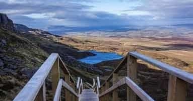 Wooden boardwalk leading to panoramic moorland hiking views in Ireland