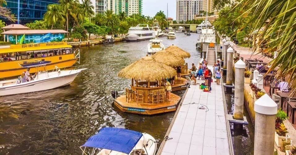 Riverside tiki docks and boats along urban canal, waterfront stroll