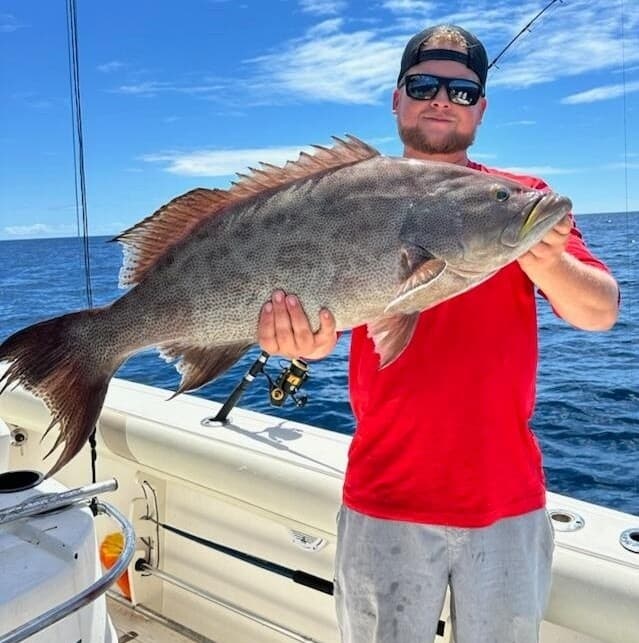 Angler holding large grouper on boat during Myrtle Beach charter
