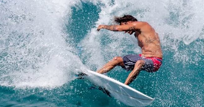 Surfer carving spray on a turquoise breaking ocean wave