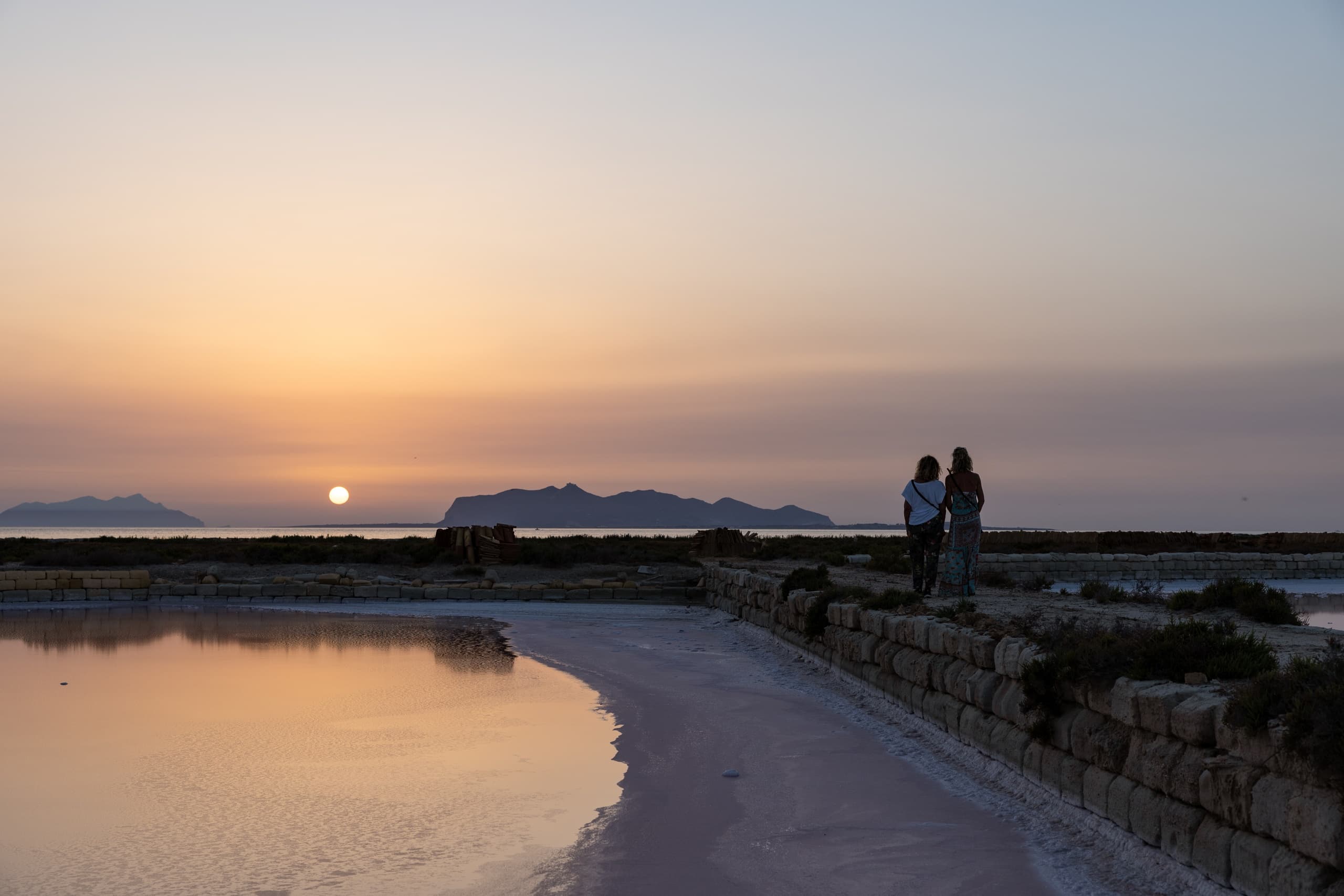 Couple walking along salt ponds at sunset on coastal flats