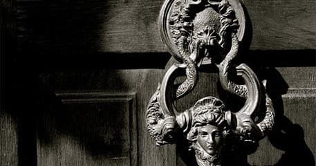 Ornate door knocker on aged wooden door at historic entryway