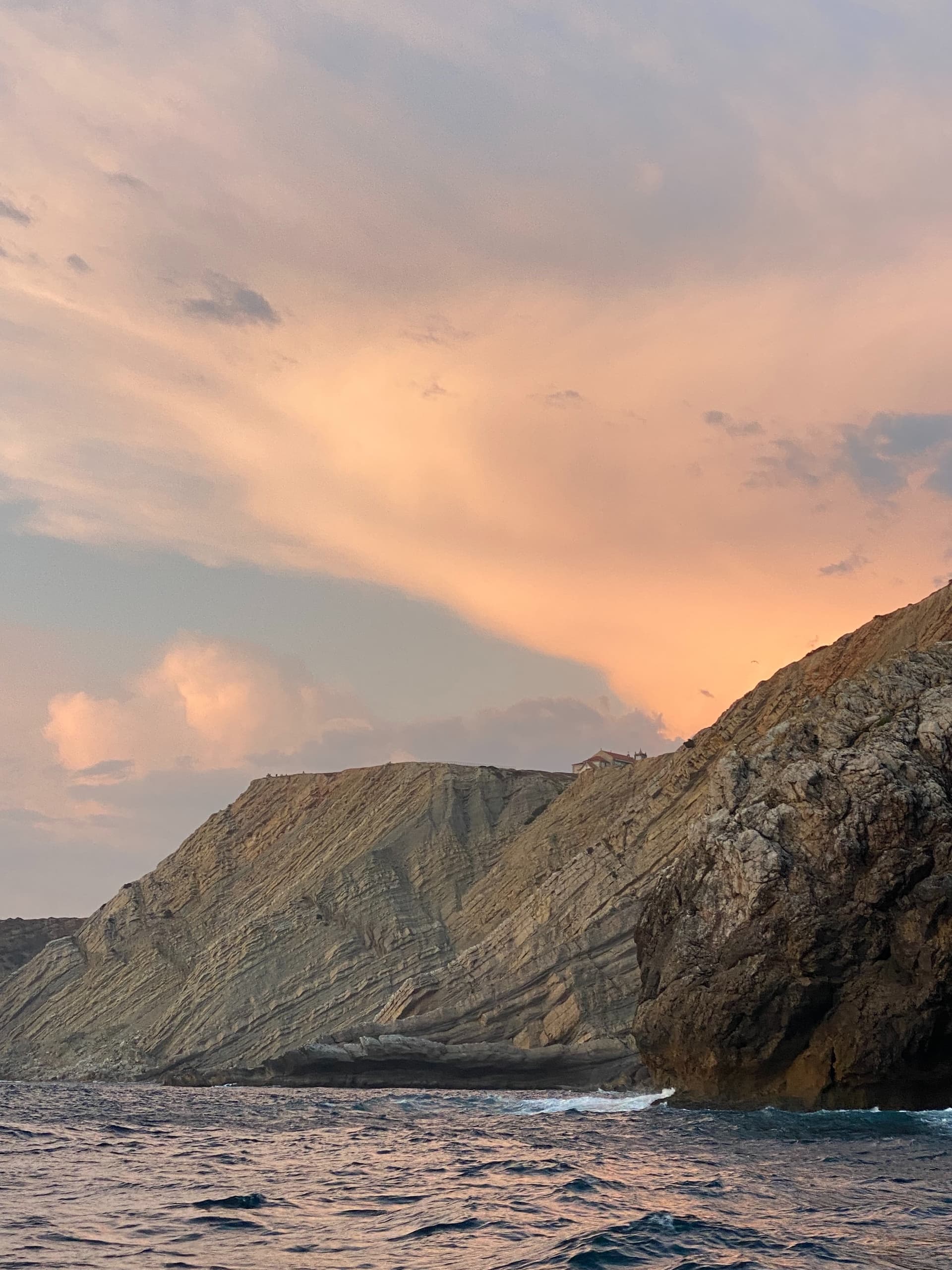 Rocky cliff at sunset over open sea, dramatic coastal vista