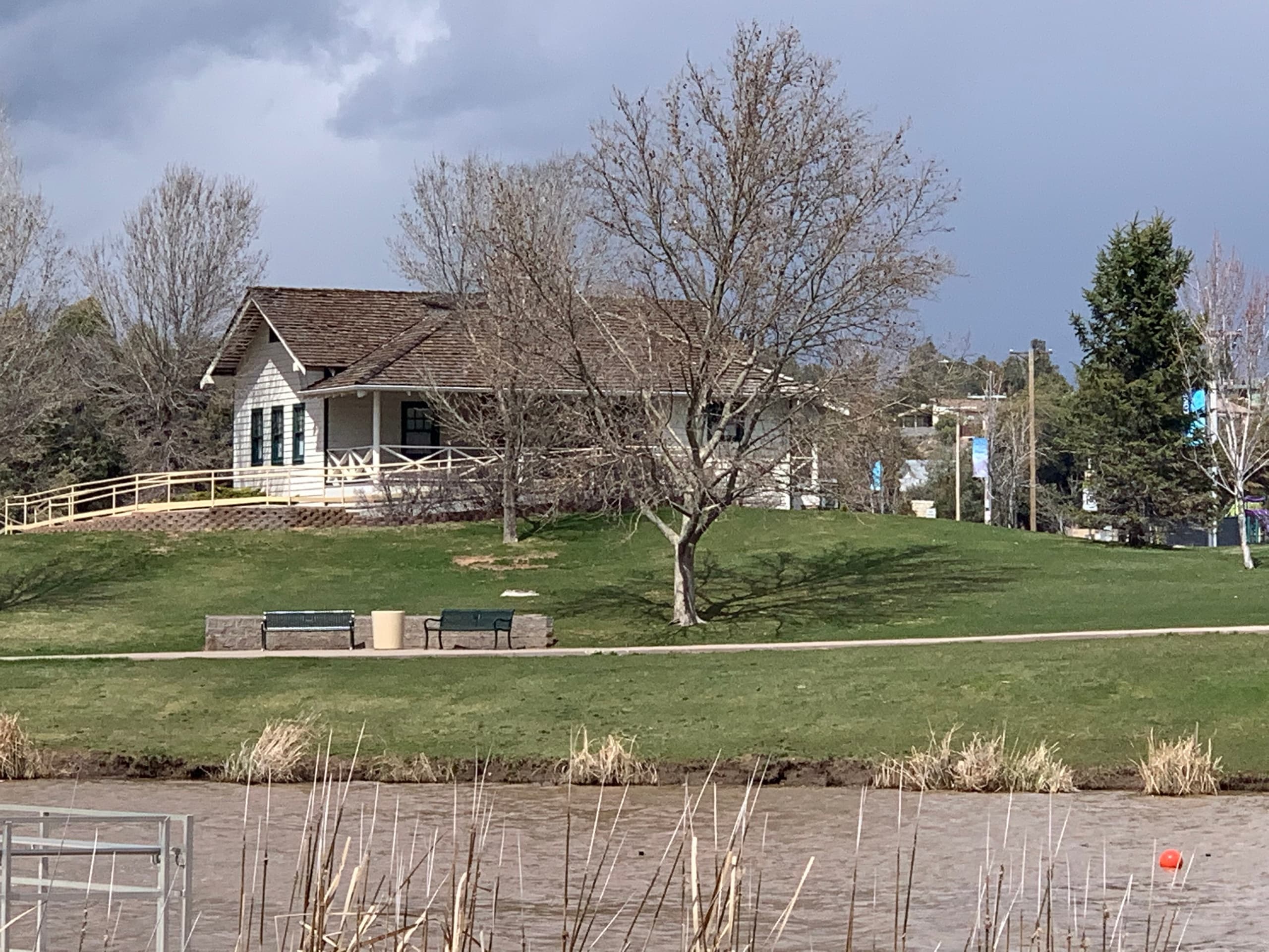 Lakeside park with benches and grassy hill near suburban trail