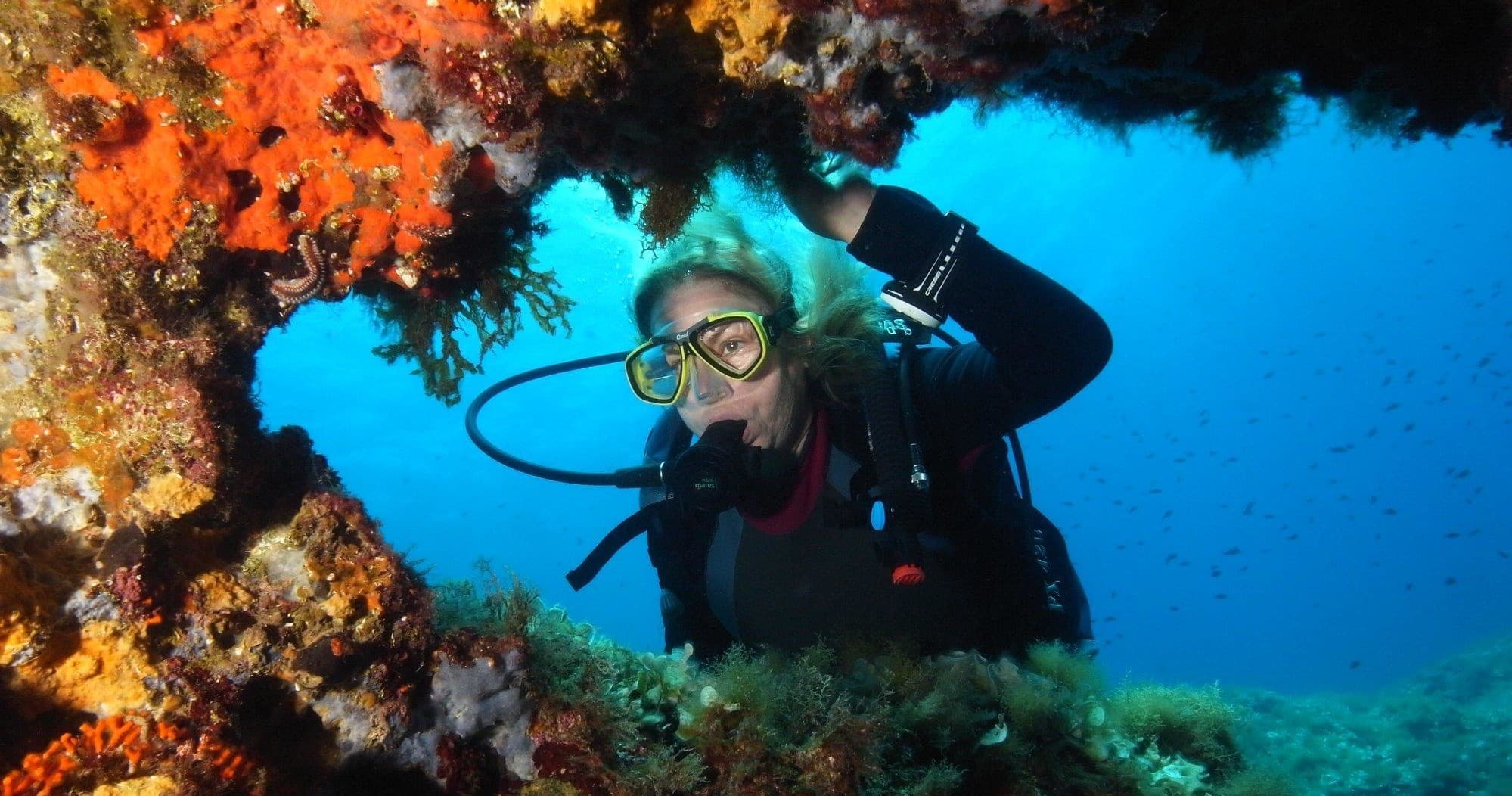 Scuba diver exploring colorful coral arch in tropical reef