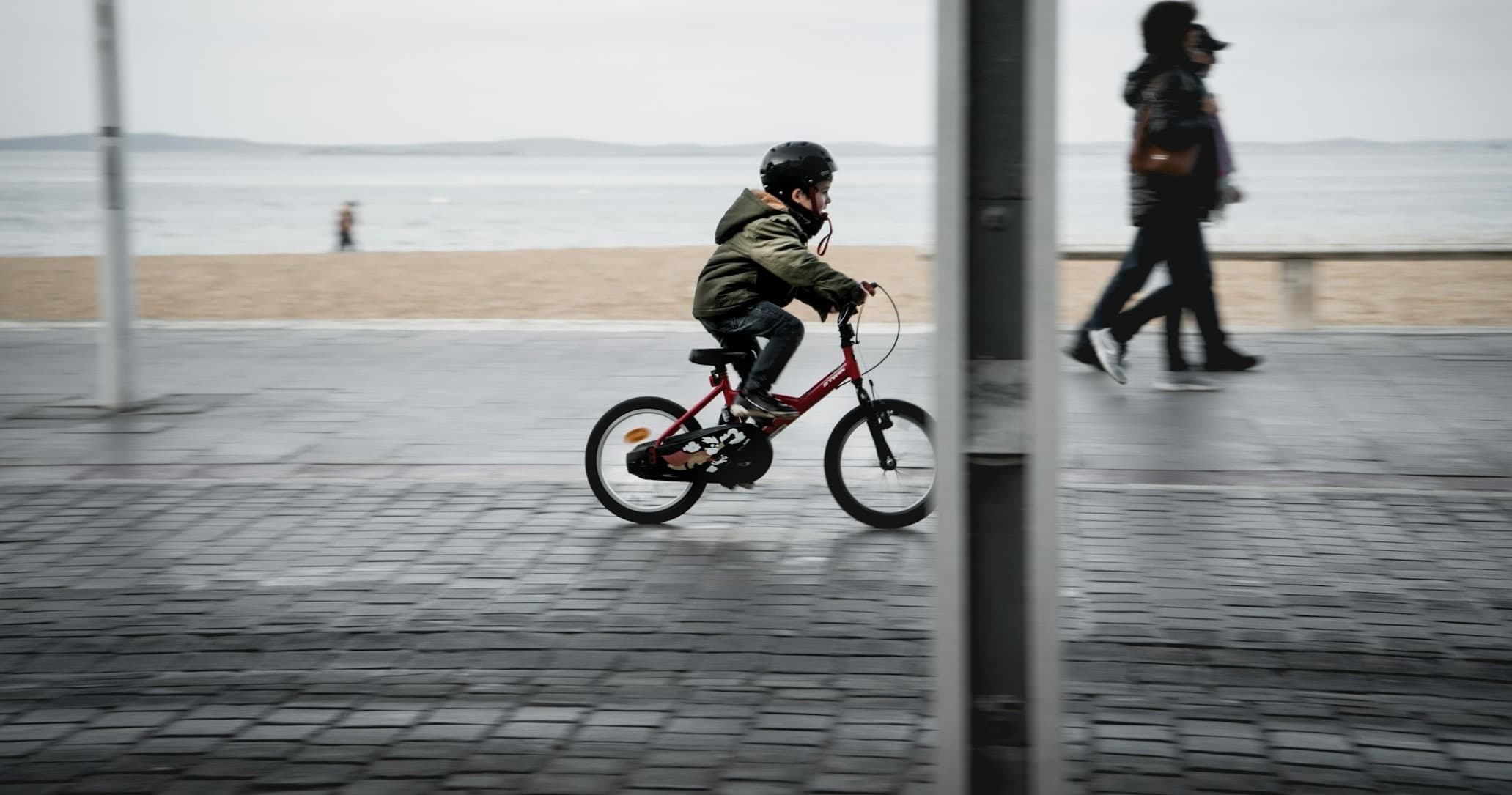 Child riding bicycle along seaside promenade, motion capture