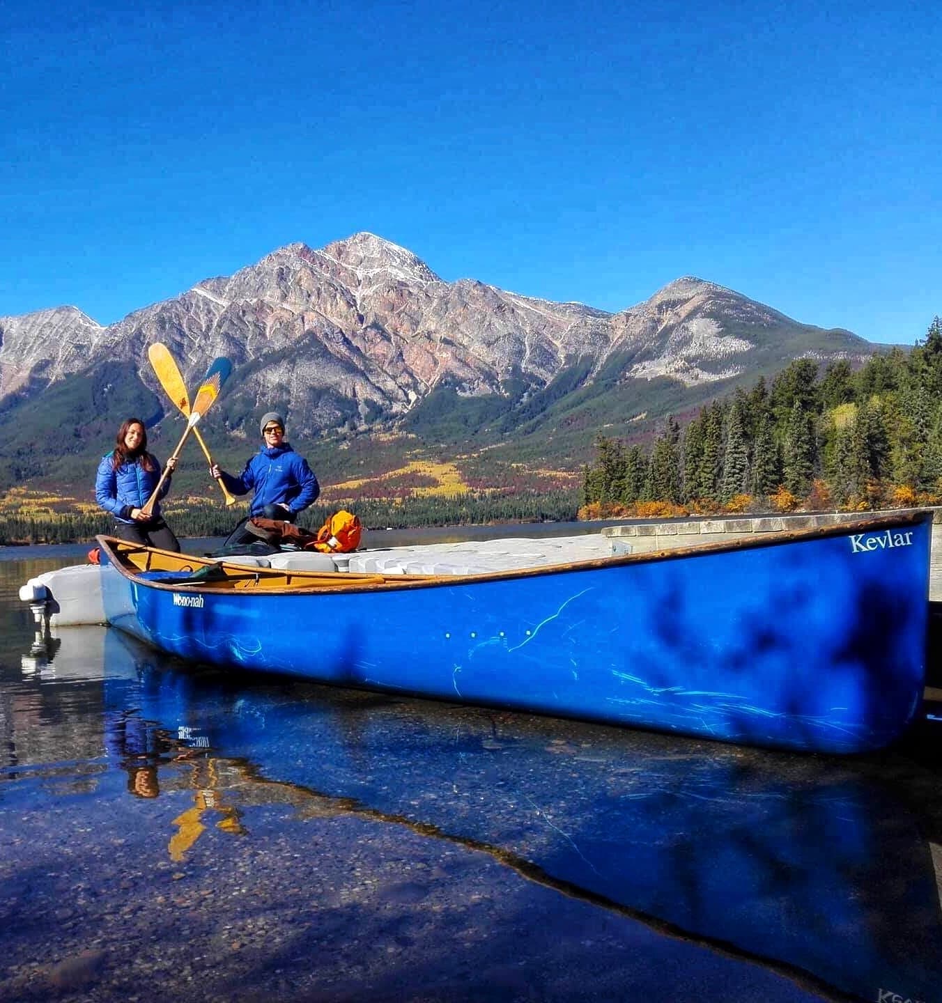 Two paddlers in blue canoe on mountain lake adventure