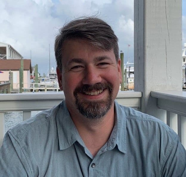 Birding guide smiling on waterfront porch with marina, Beaufort