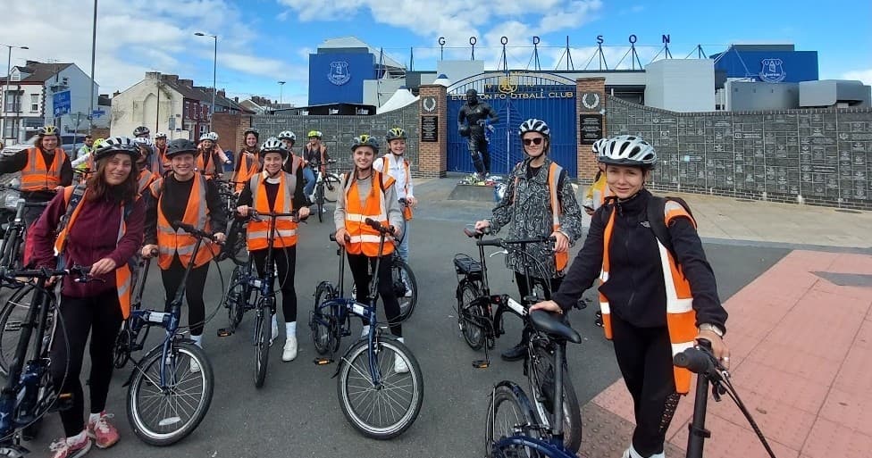 Guided bike tour group on Liverpool seafront in hi-vis vests