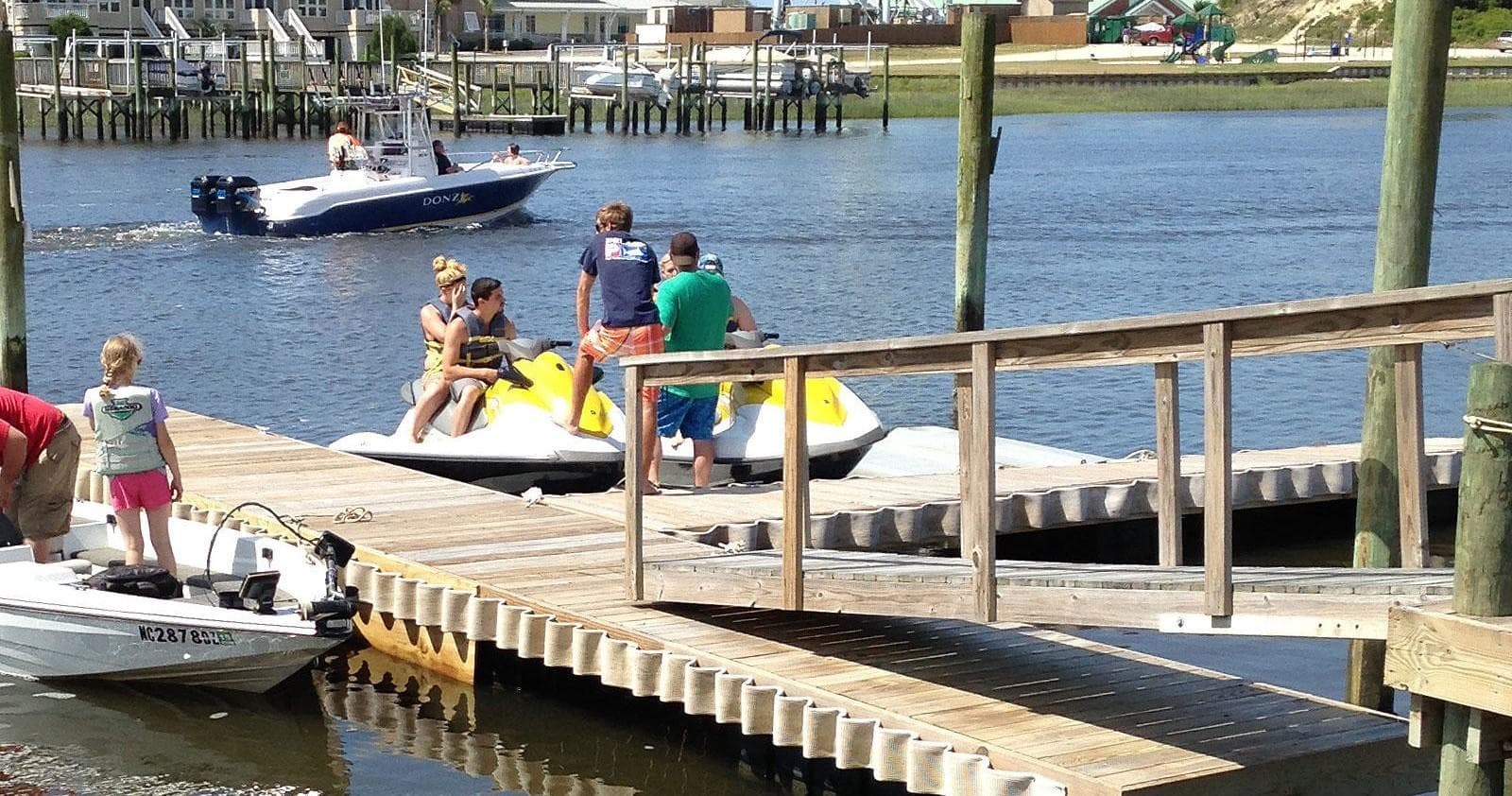 Jet skis and small boats launching from marina dock on sunny day