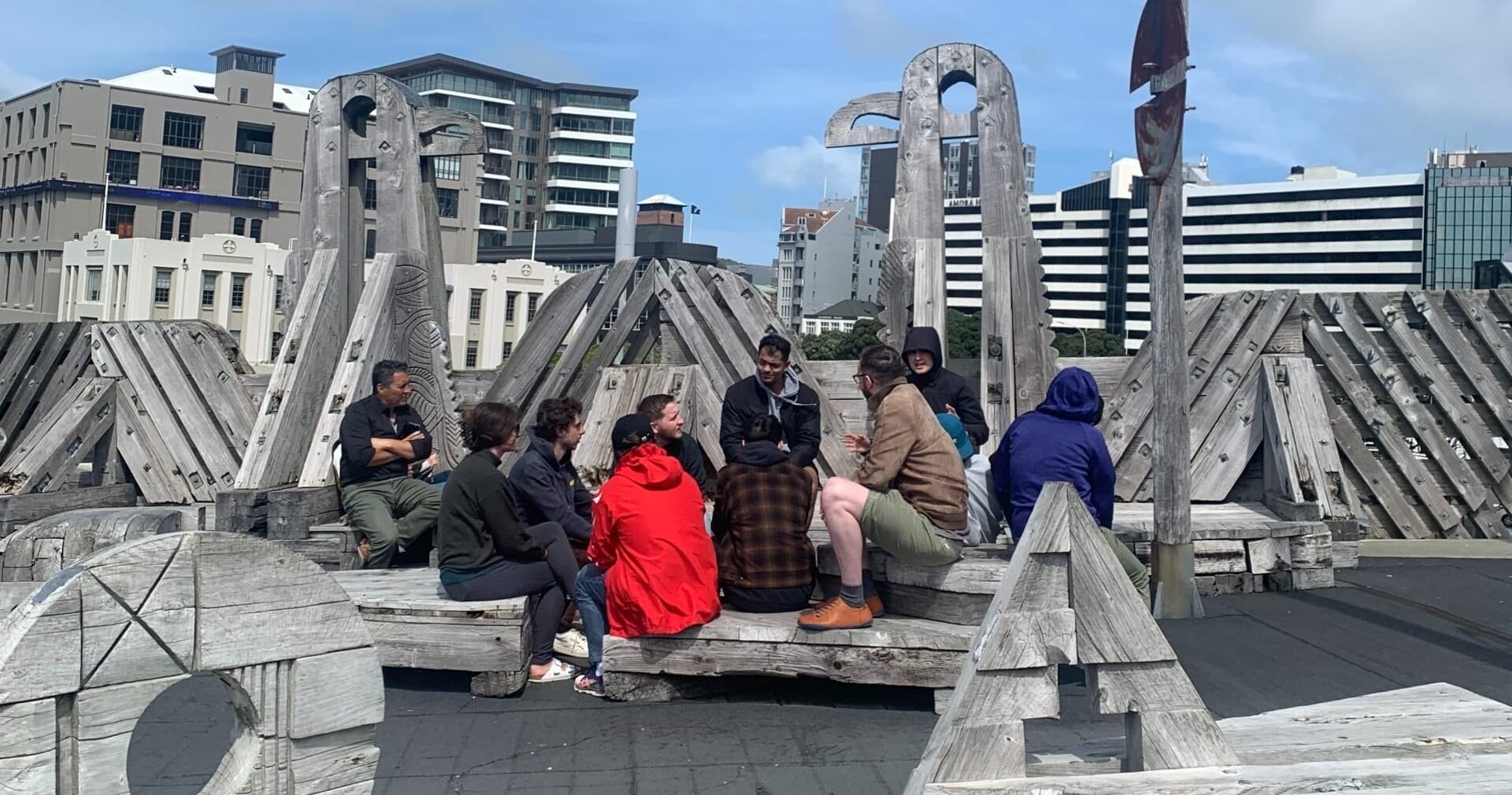 Group gathering on waterfront timber sculpture at urban pier