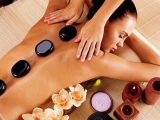 Hot stone massage on back with flowers in spa